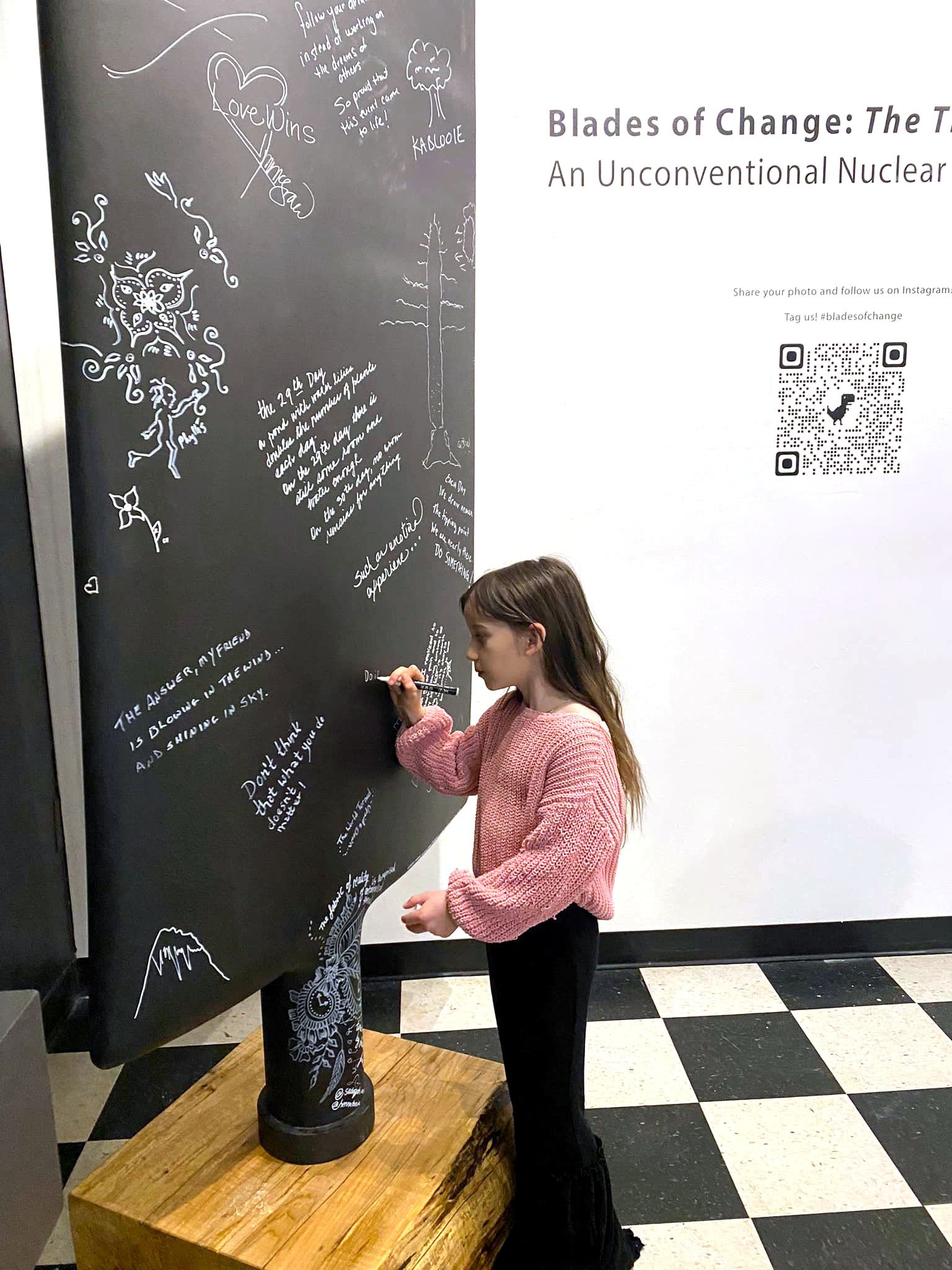 Young girl writing on an interactive nuclear sculpture at FOGUE Studios